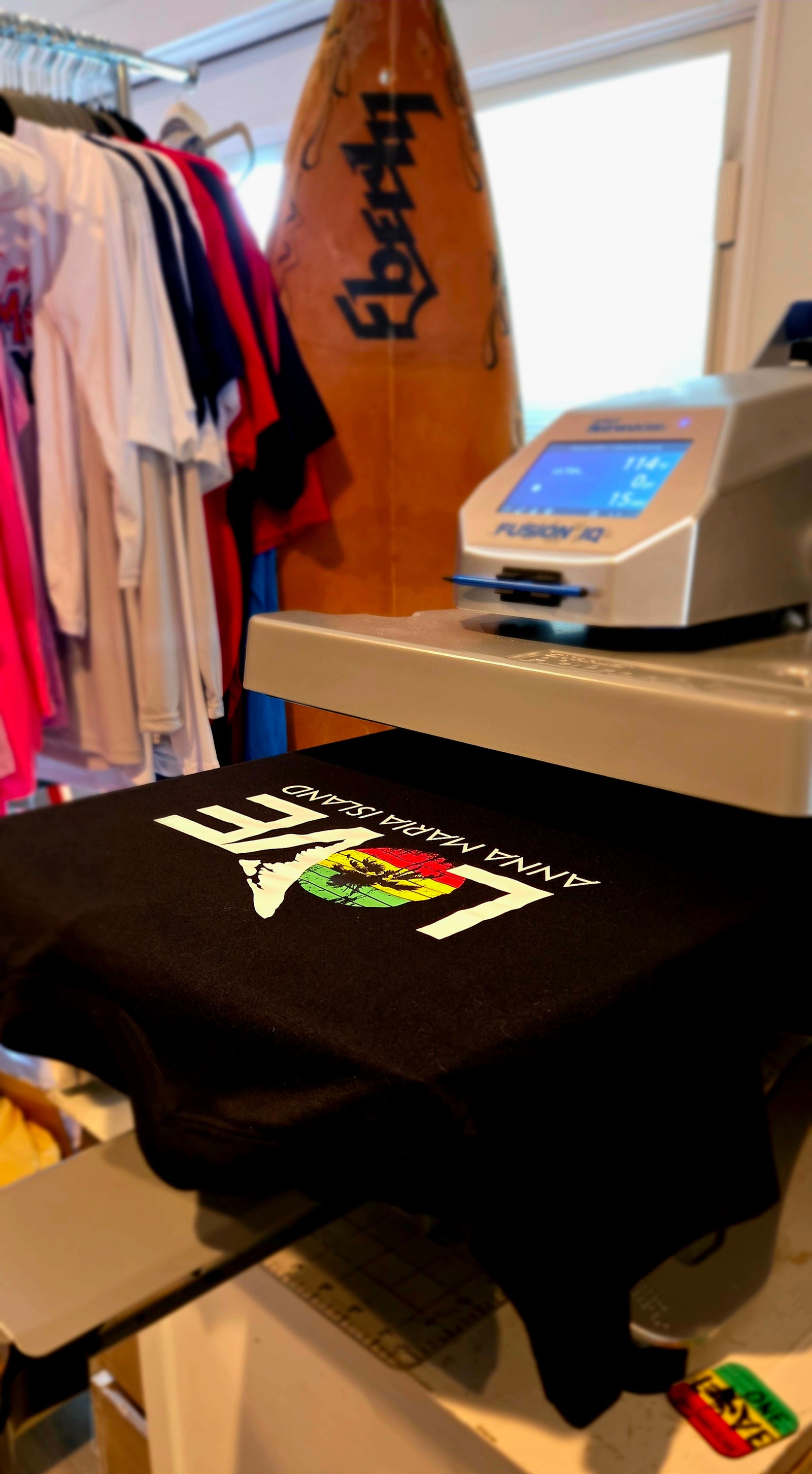 Black OneLoveAMI T-shirt being heat pressed at Gnarly Mangrove Designs shop in Bradenton, Florida.