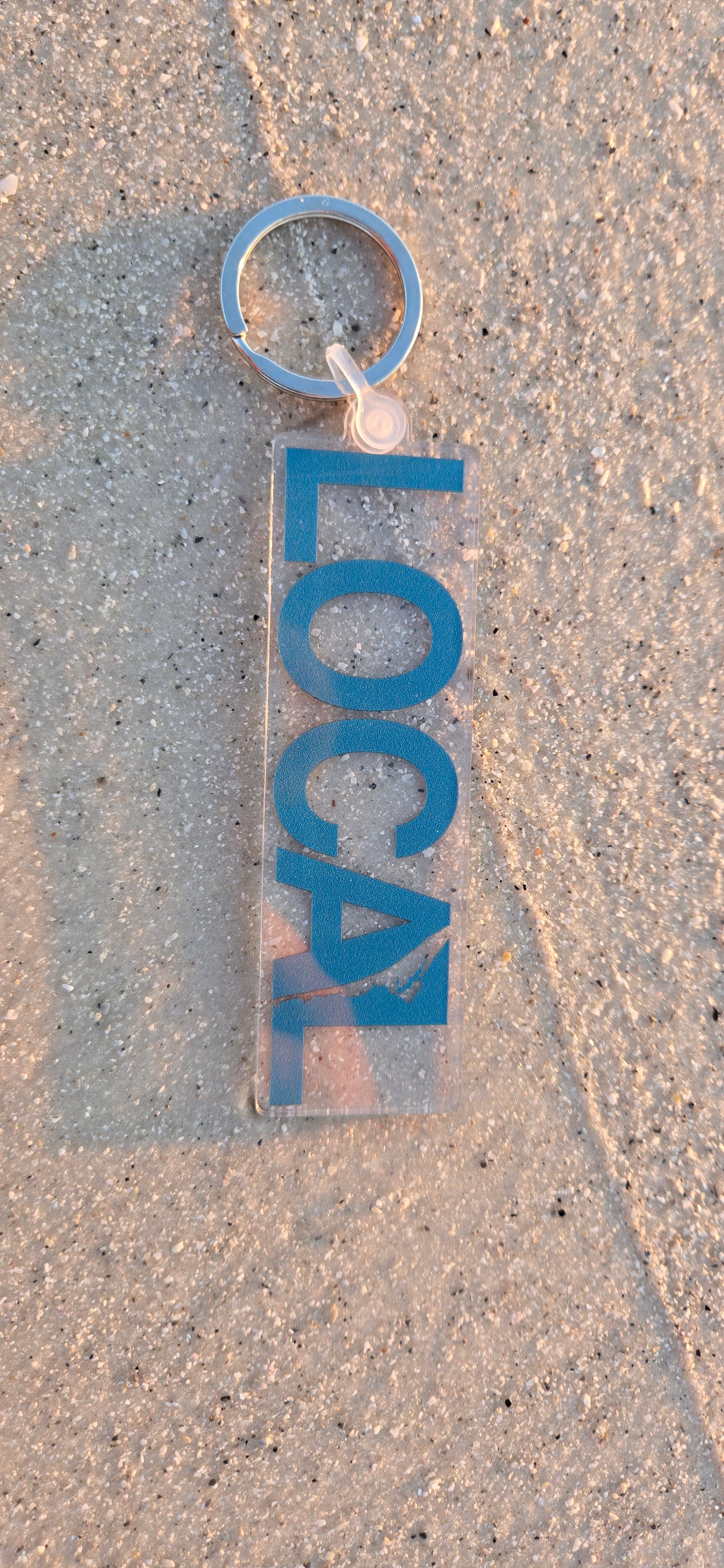 Blue Local keychain with the shape of Anna Maria island between the A and L