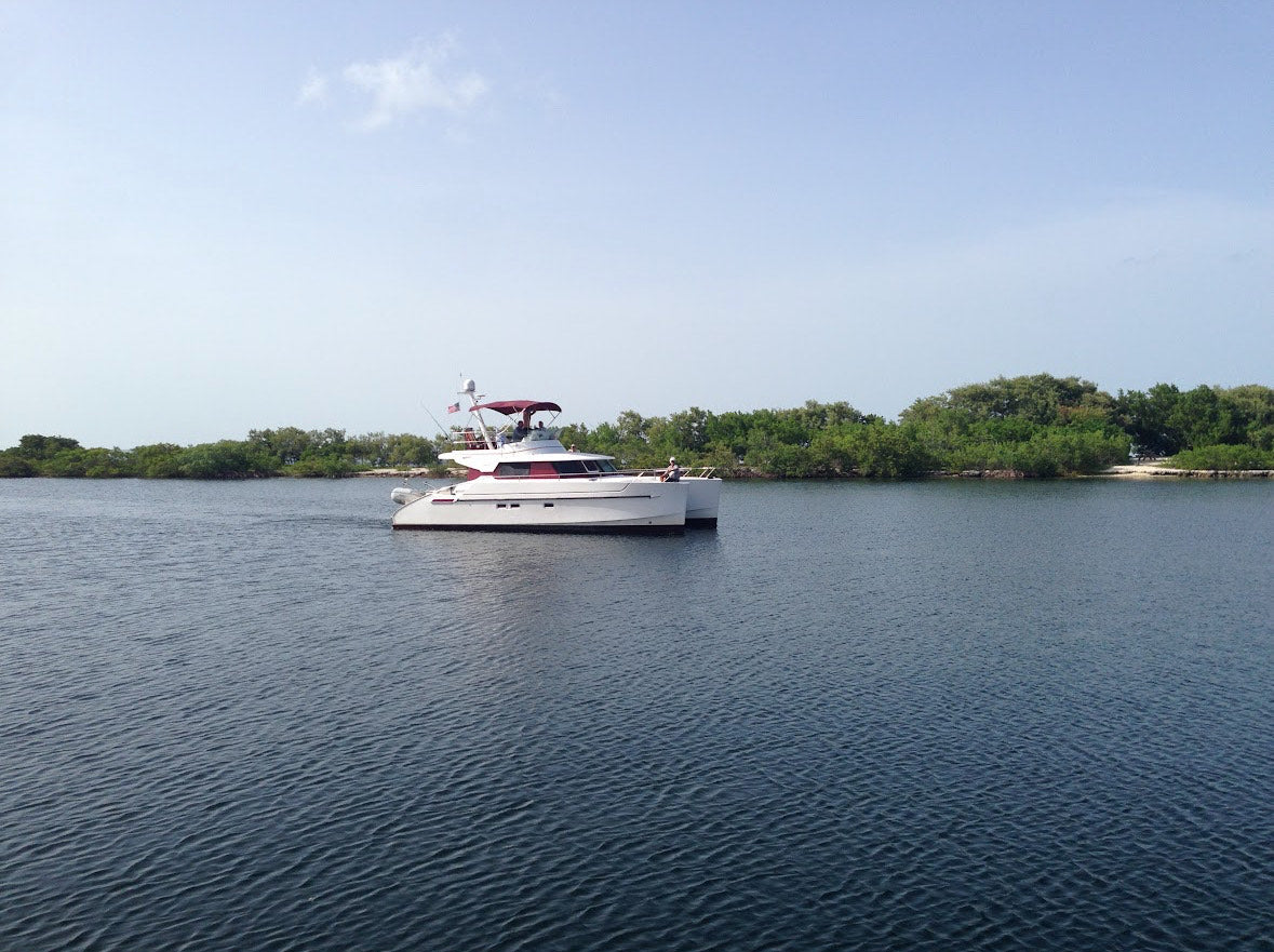 A big red and white boat cruising up the Manatee River, where Gnarly Mangrove Designs first started in Bradenton.